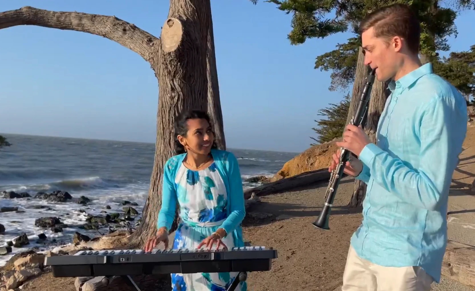 Corbett playing clarinet beside a keyboardist by the ocean